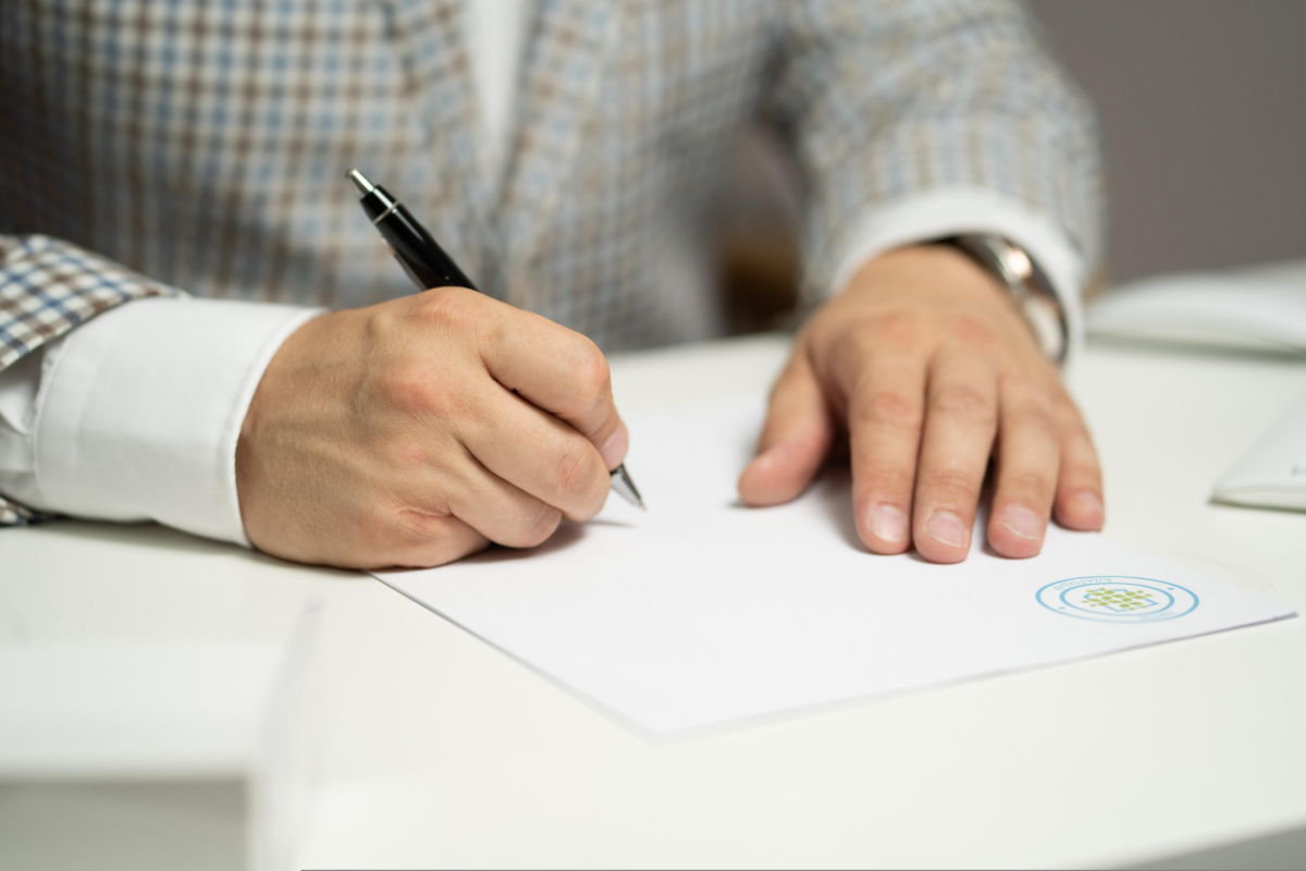 Person schreibt mit einem Kugelschreiber auf einem Papier.
