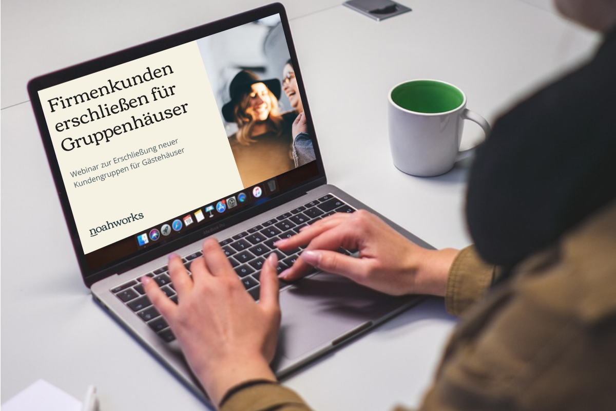 Frau sitzt vor einem geöffneten Laptop. Dort steht "Firmenkunden erschließen für Gruppenhäuser".