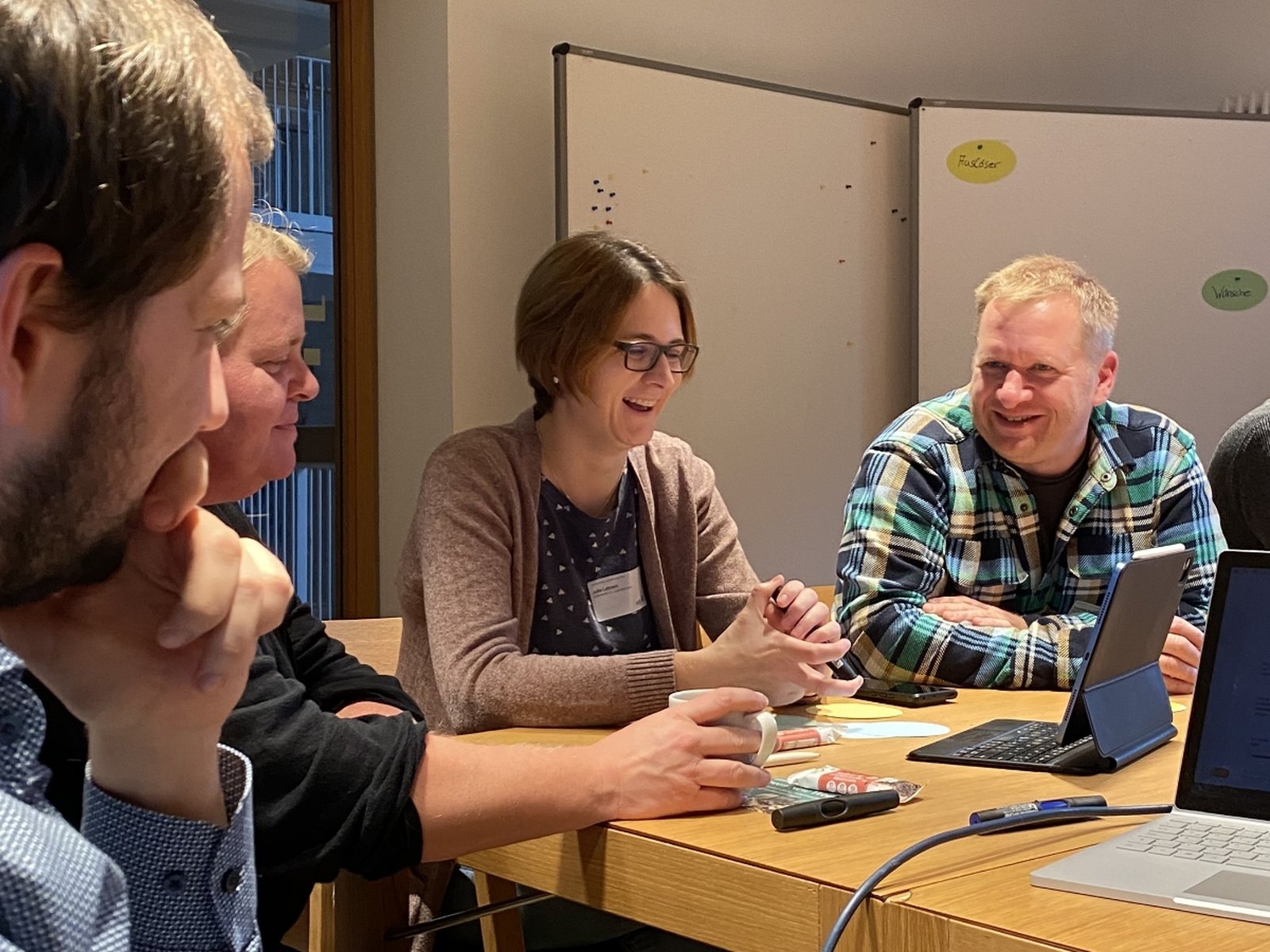 Vier Workshop-Teilnehmer sitzen am Tisch und lachen