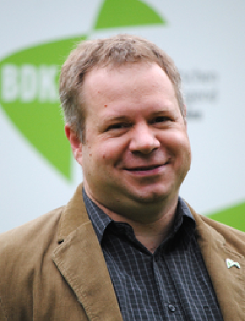 Lächelnder Armin Hesse vor dem Logo des BDKJ NRW.